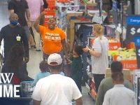 Man raising hand inside a crowded store aisle.