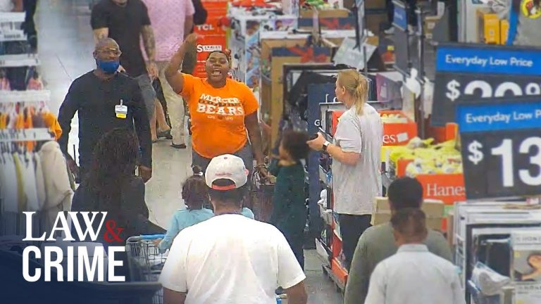 Man raising hand inside a crowded store aisle.