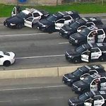 Police cars surround white vehicle on highway