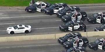 Police cars surround white vehicle on highway