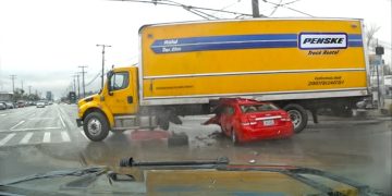 Truck crashed into red car at intersection.