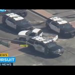 Police cars surround vehicle in pursuit scene.