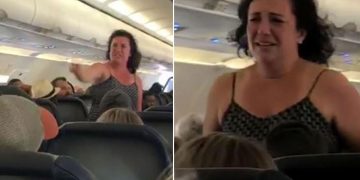 Passenger standing and speaking on airplane.