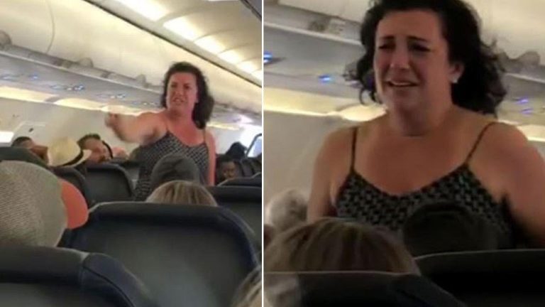 Passenger standing and speaking on airplane.