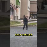 Police officer walking in shopping center parking lot.