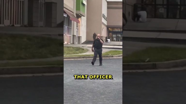 Police officer walking in shopping center parking lot.