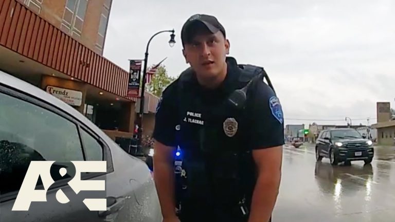 Police officer talking to driver on rainy street.