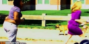 Two women running outside with small dog following.