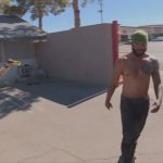 Police officer aiming Taser at shirtless man outdoors