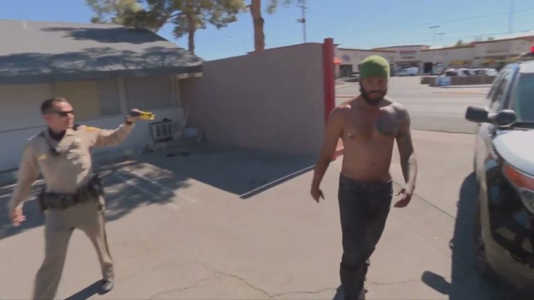 Police officer aiming Taser at shirtless man outdoors