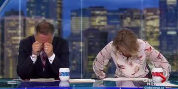 News anchors laughing at a desk on live broadcast.