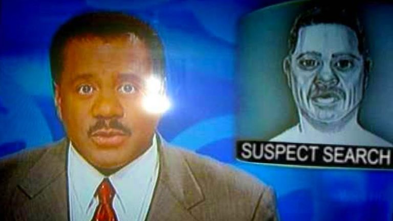 News anchor reporting suspect search on television broadcast.