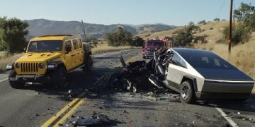 Car crash involving yellow and silver vehicles on road.