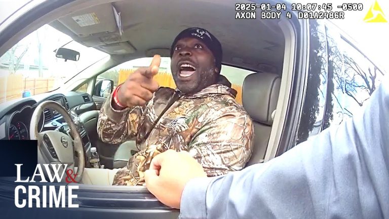 Man seated in car, pointing and talking