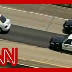 Police chase white car on highway.