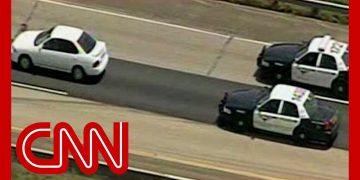 Police chase white car on highway.