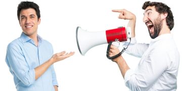 Man smiling at another man with megaphone