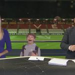 News anchors laughing in stadium studio.