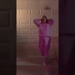 Person dancing energetically in pink outfit outside garage