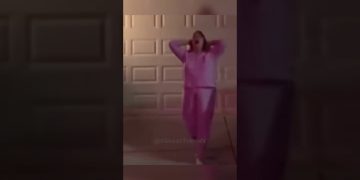 Person dancing energetically in pink outfit outside garage