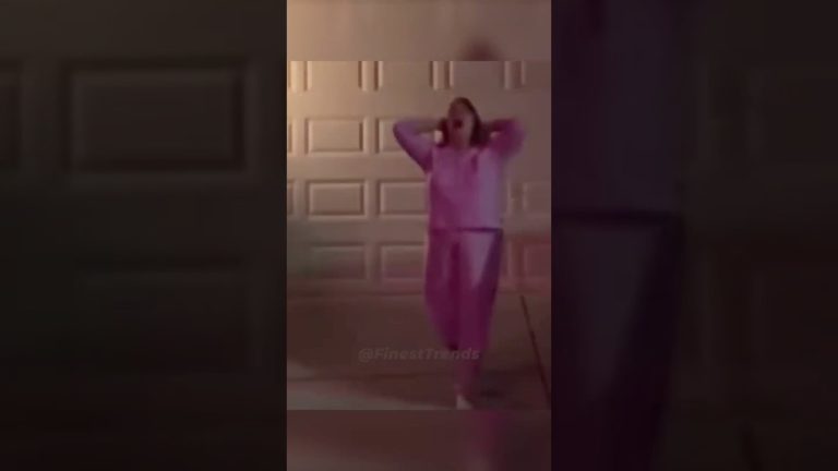 Person dancing energetically in pink outfit outside garage