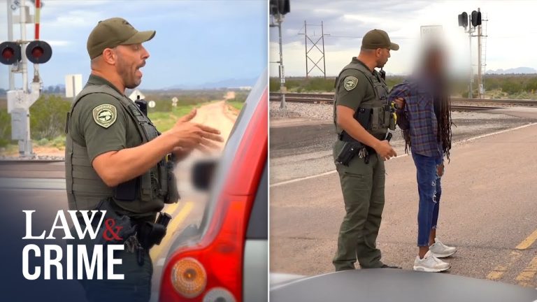 Police officer interacting with person near railroad crossing.