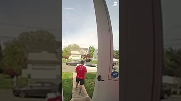 Person leaving house wearing a red sports jersey.