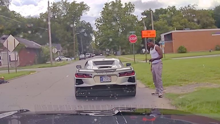 Man standing by sports car near stop sign.