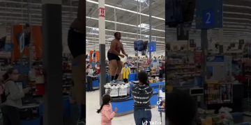 Person dancing on checkout stand in busy store.