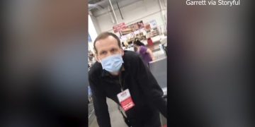 Masked grocery employee at checkout counter