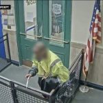 Person entering police station through door with clipboard.