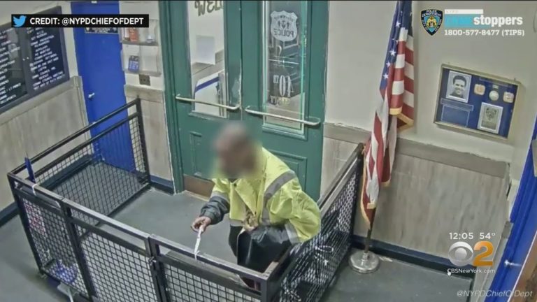 Person entering police station through door with clipboard.