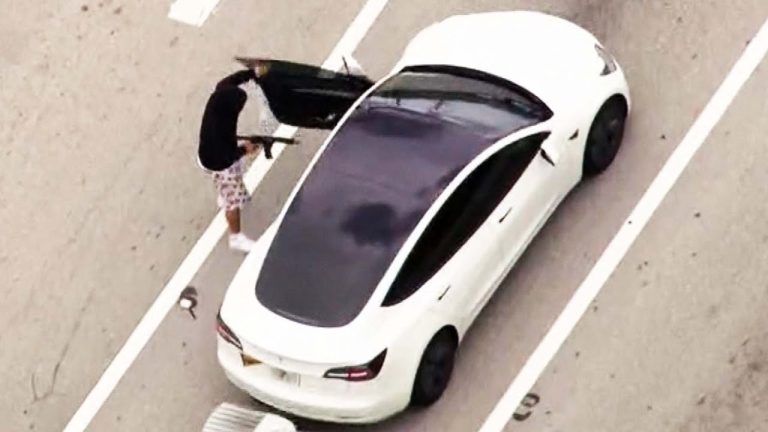 Person entering white car on the road.