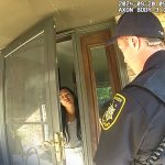 Police officer talking to woman at door