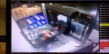 Drive-thru employee hands item to car passenger