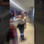 Person raising hand at airport counter.