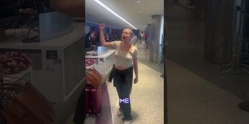 Person raising hand at airport counter.