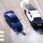 Police car pursuit of a blue vehicle on highway.