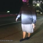 Person walking on road shoulder at night recorded by dashcam