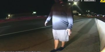 Person walking on road shoulder at night recorded by dashcam