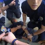 Police officers restraining suspect on ground