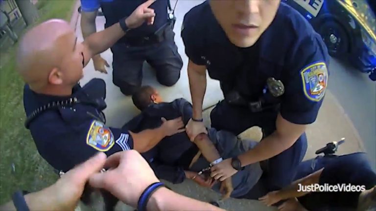 Police officers restraining suspect on ground