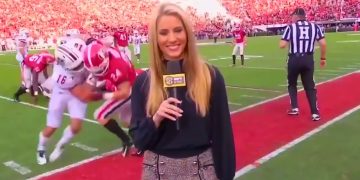 Reporter on football field during game.