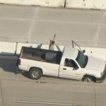 White truck stopped on highway with armed person.