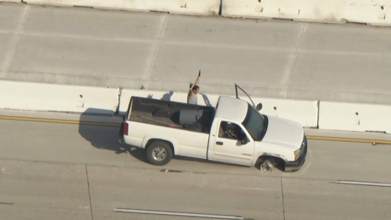 White truck stopped on highway with armed person.