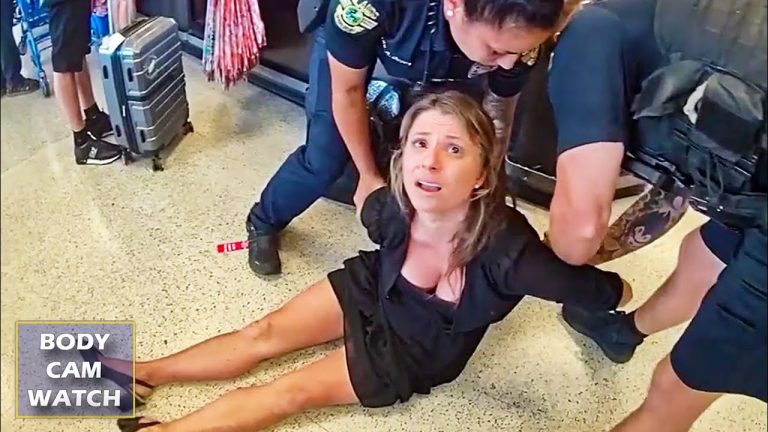 Person detained by airport security officers on floor.