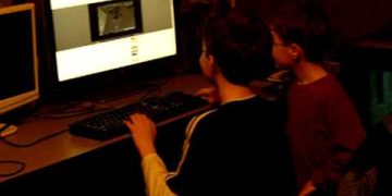 Children playing computer game together at desk.