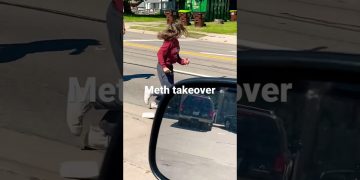 Person running across street with cars and dumpsters.