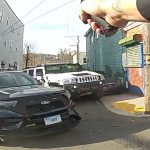 Police car and hand holding taser in street scene.