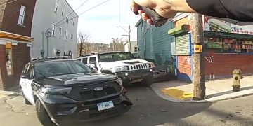 Police car and hand holding taser in street scene.